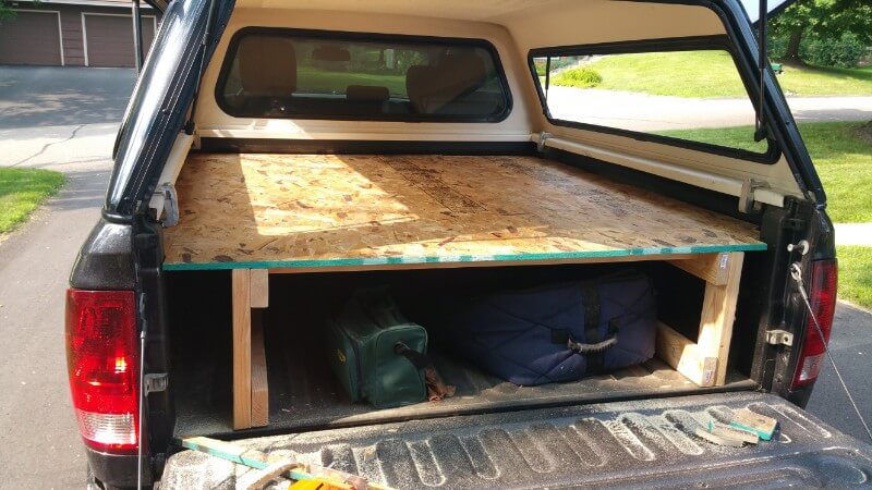 wood frame in truck bed with plywood across top as sleeping platform