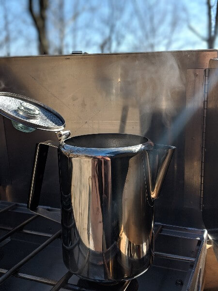 stainless percolator on camp stove to make cowboy camping coffee