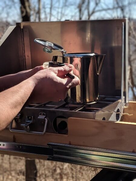 course ground coffee dumped into pot on camping stove