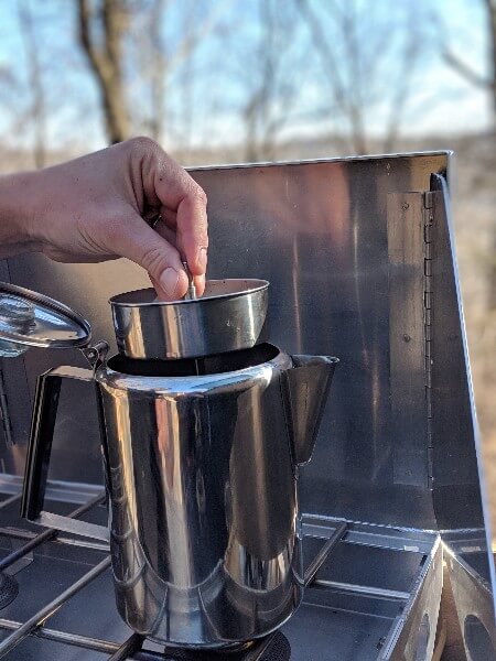 insert percolator apparatus into stainless percolator on camp stove