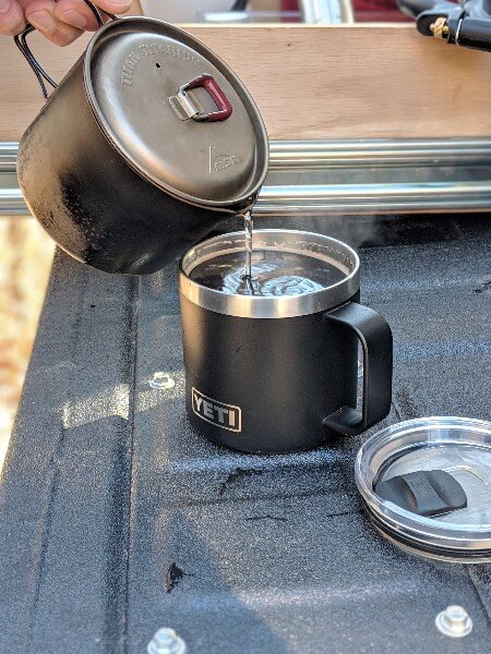 pouring camping coffee from msr titanium kettle into yeti mug