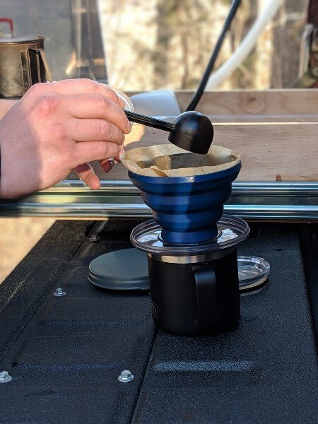 dumping coffee grounds into pour over camping coffee