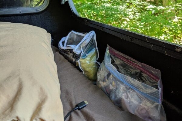 "Closet" beside mattress/under bed rails - repurposed bags from sheets are great for uses like this