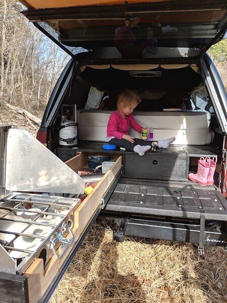 child playing on truck sleeping platform with slide kitchen drawer out