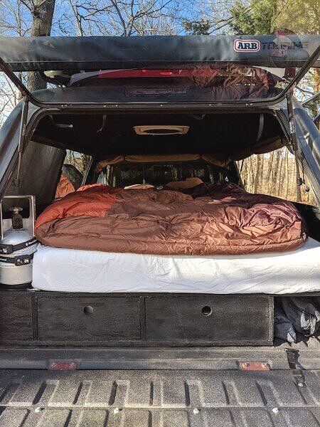 interior of truck shell camper mattress and sleeping bag on sleeping platform