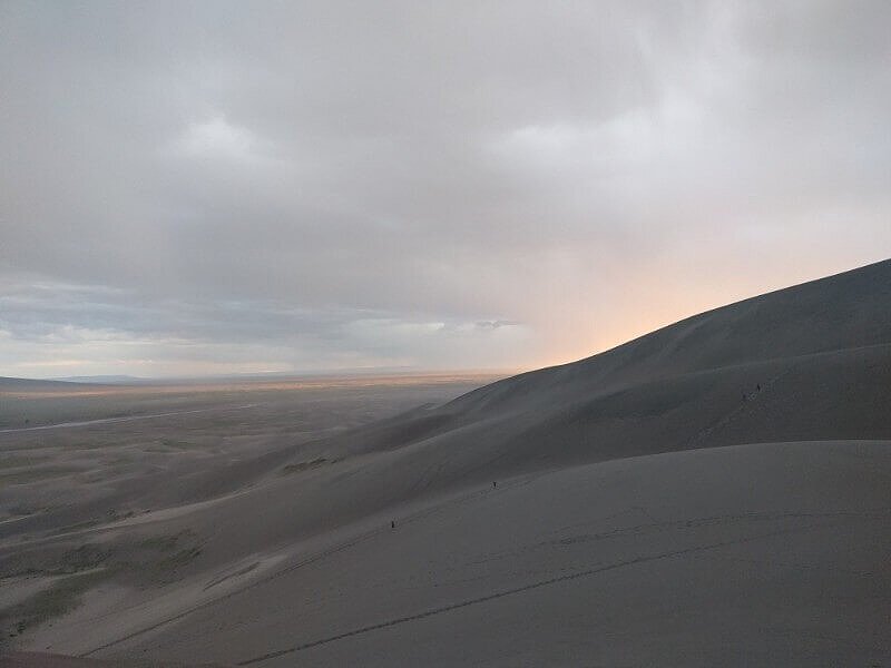 orange sunset behind sand dunes national park colorado before rain