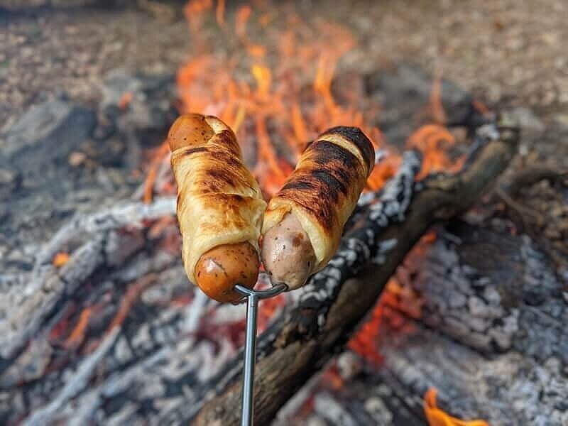 Pigs in a blanket over the campfire as a fun camping lunch for kids.