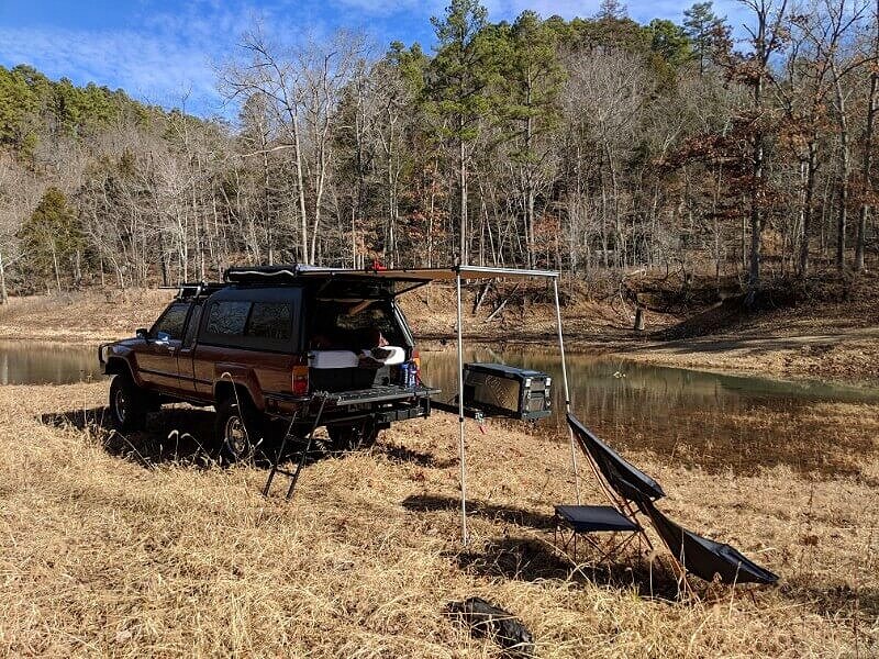 truck camping gear in use by a lake in an pickup truck camper