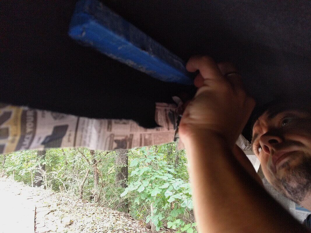 Installing a camper shell liner against a window frame.