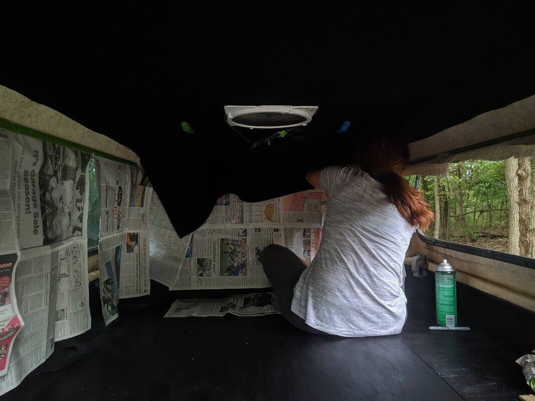 Woman installing a camper shell liner to the ceiling of a truck shell.