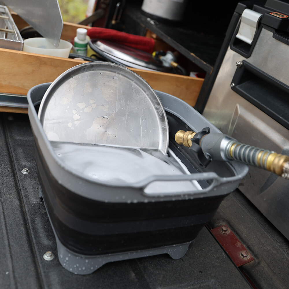 demonstrating doing dishes in portable camp sink while camping