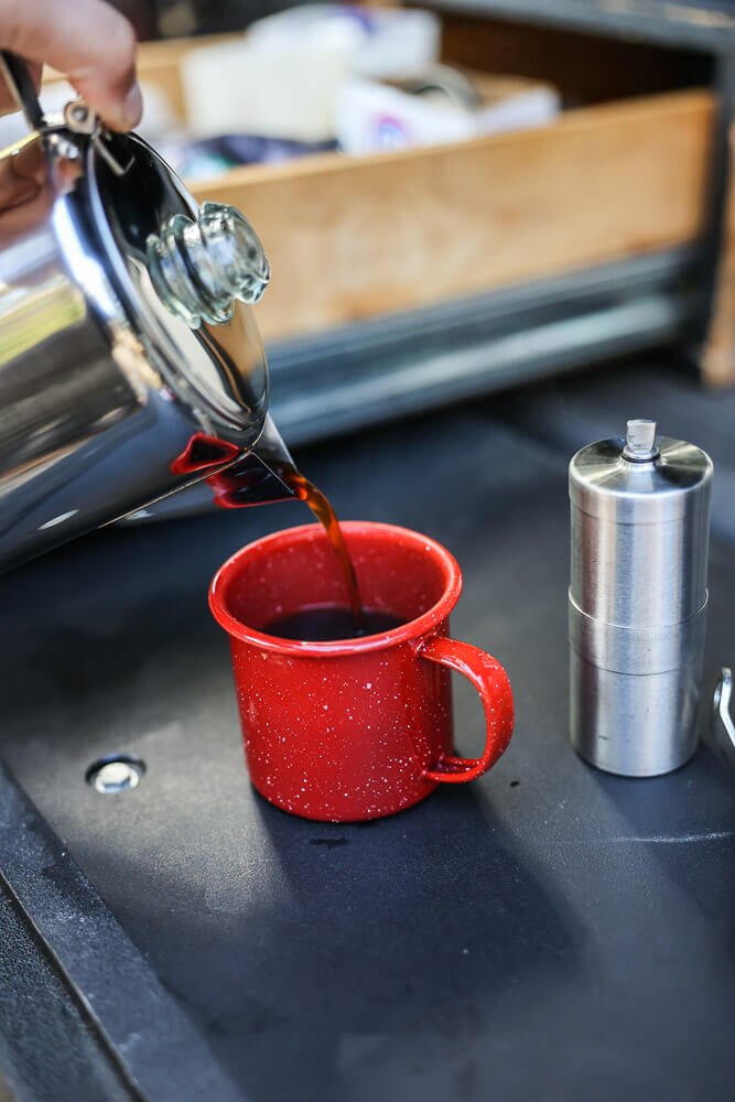 pouring coffee from the camping percolator into a camping mug