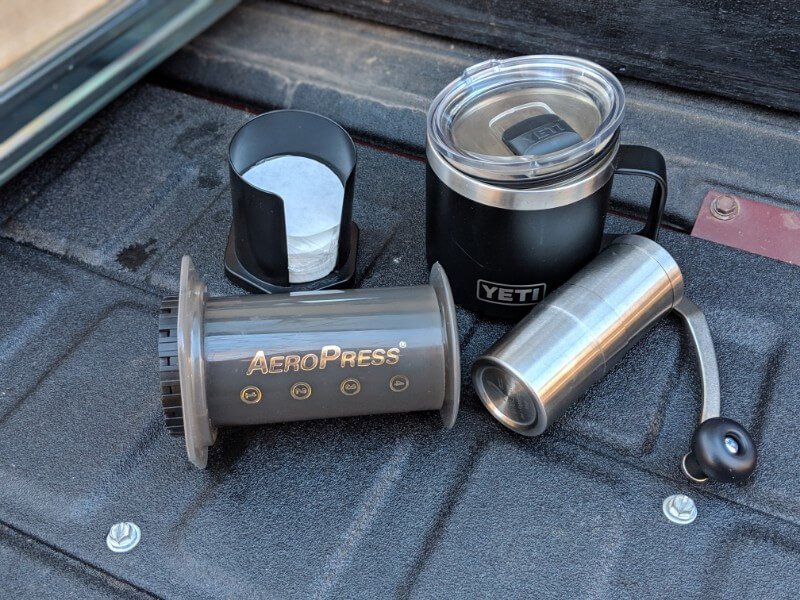 aero press coffee supplies including filters, grinder, and camping mug