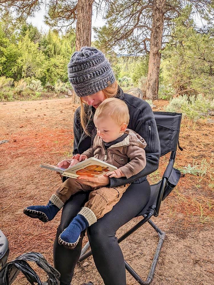 baby reading with mom in camp chair while camping