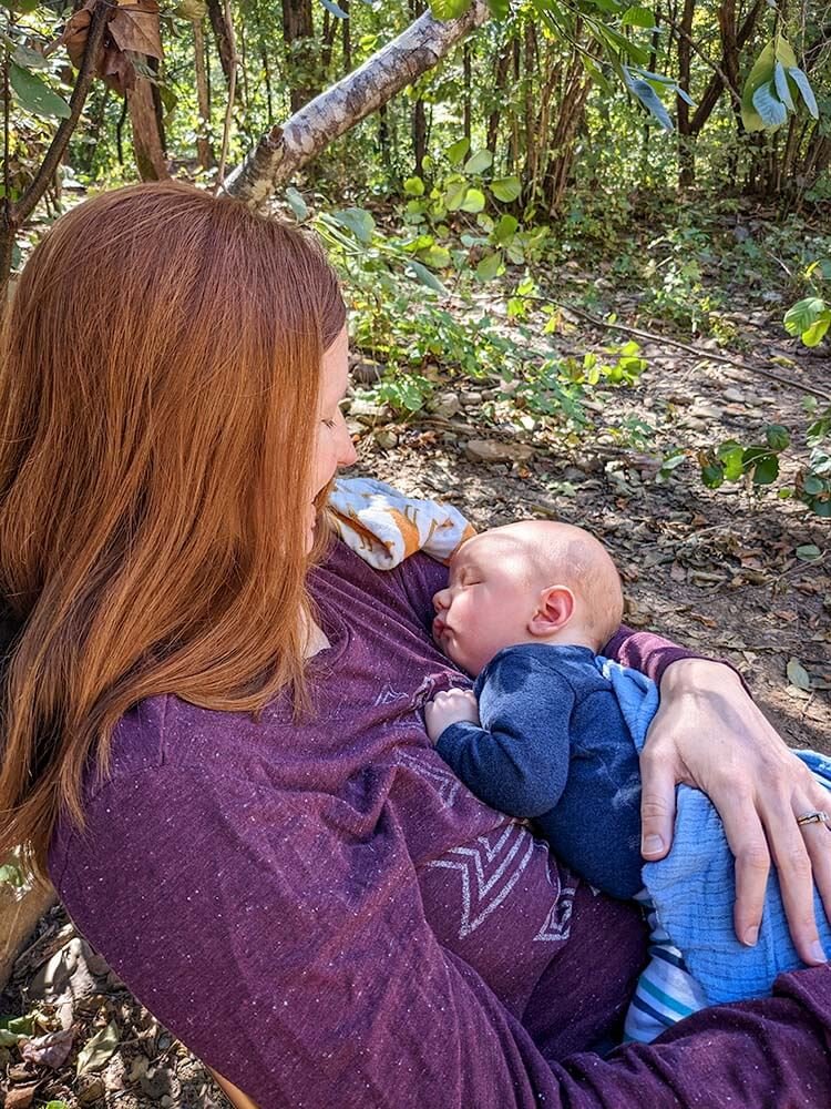 mom relaxed in comfortable camp chair for nursing baby while camping