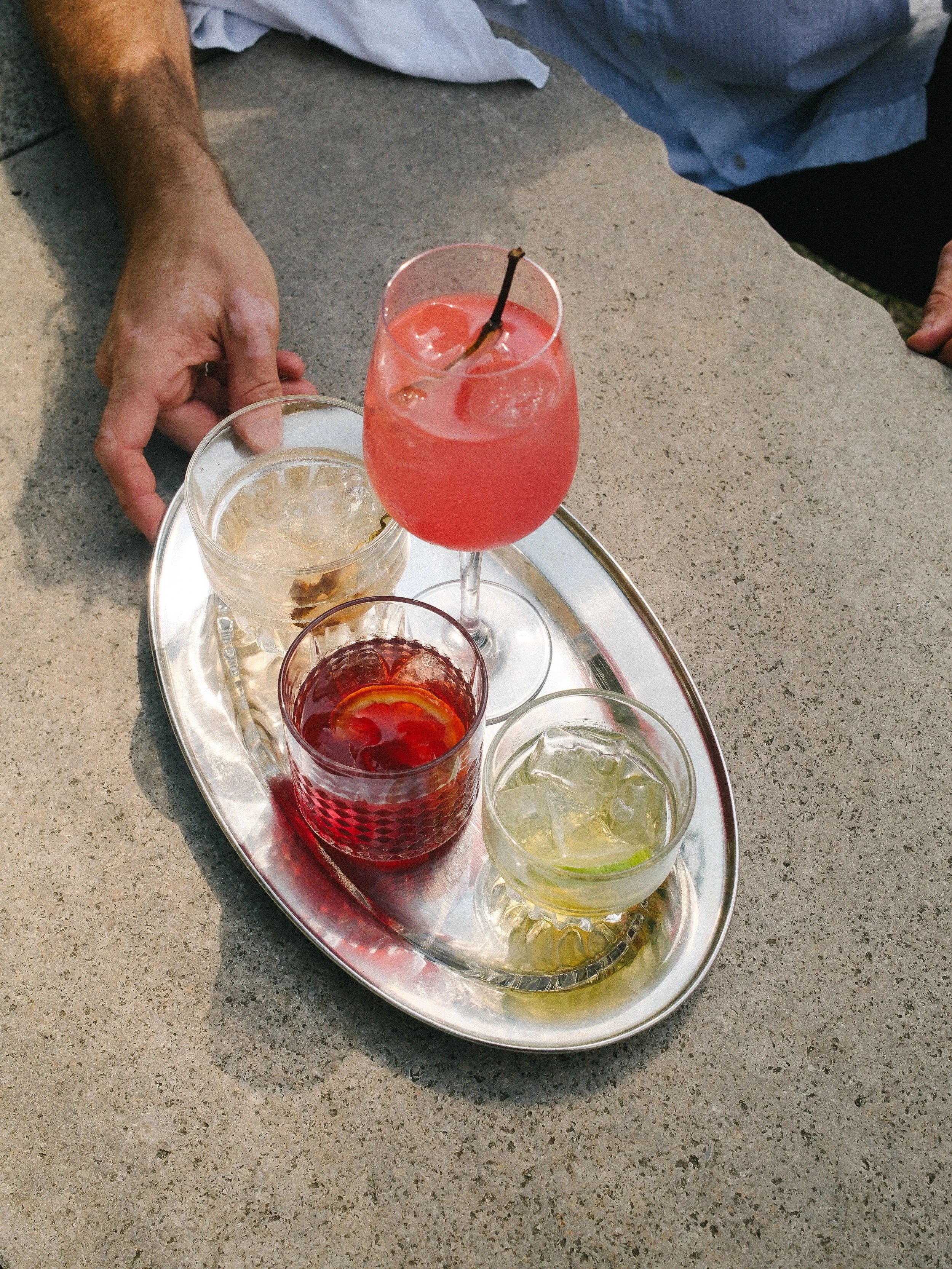Silbrnes Tablett mit diversen Drinks, warmes Sonnenlicht am Abend