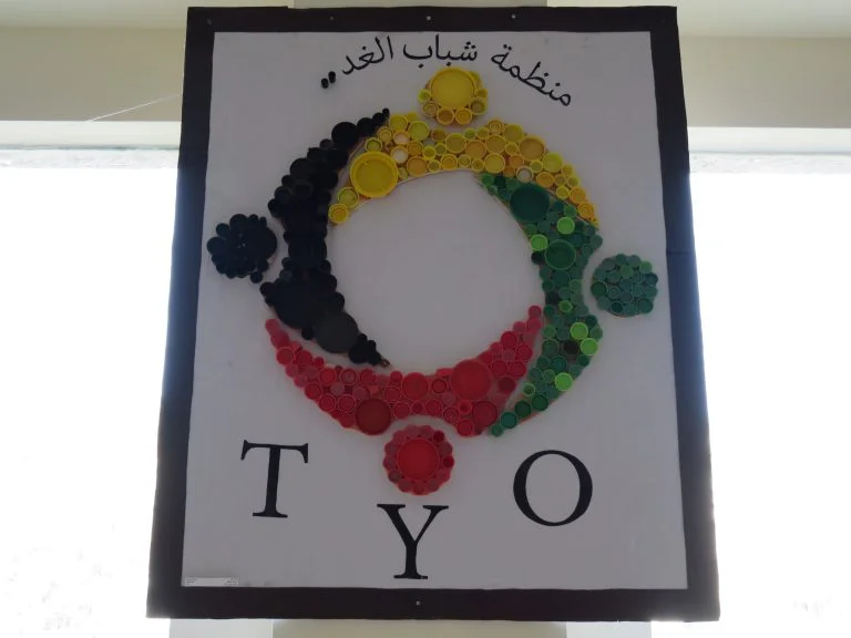 Plastic bottle caps of different shapes and colors create the TYO logo.