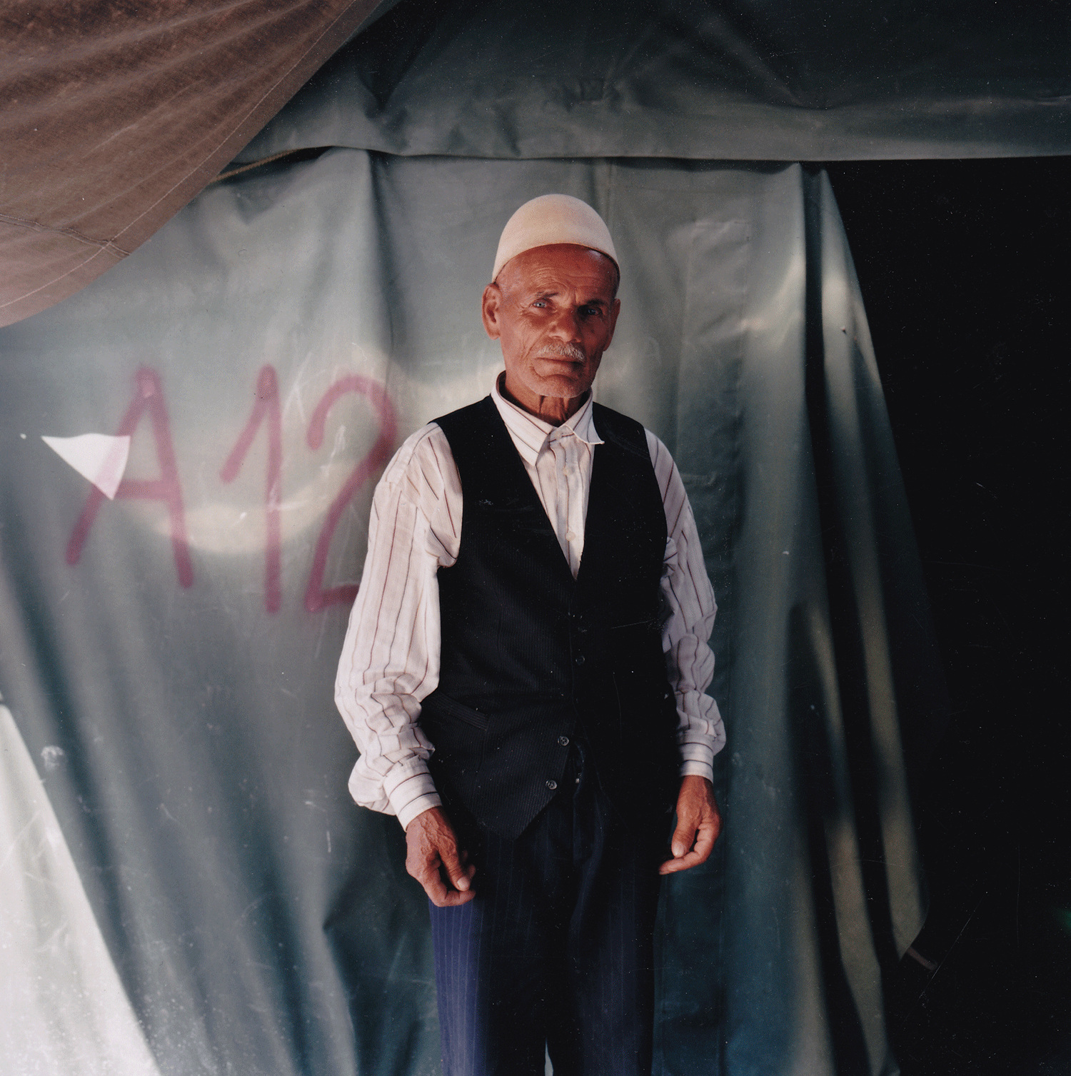 Ramadan, age 73 Neprosteno camp, Macedonia, June 10 1999. “I kept my hat from Kosova, and I will never let anyone take it from me. The Serbian police used to say, ‘what do you need this hat for?’ I didn’t let them take it. It’s our traditional Albanian hat and the Serbs don’t like it. They would order me, ‘Take off your hat.’ They wanted to throw it in the fields. I was hit by the Serbian police four or five times because of my hat. They can kill me, but I won’t take my hat off. I sit all day and long for my village. All I want is to go back to Kosova. It’s all I want. I want to be there.”
