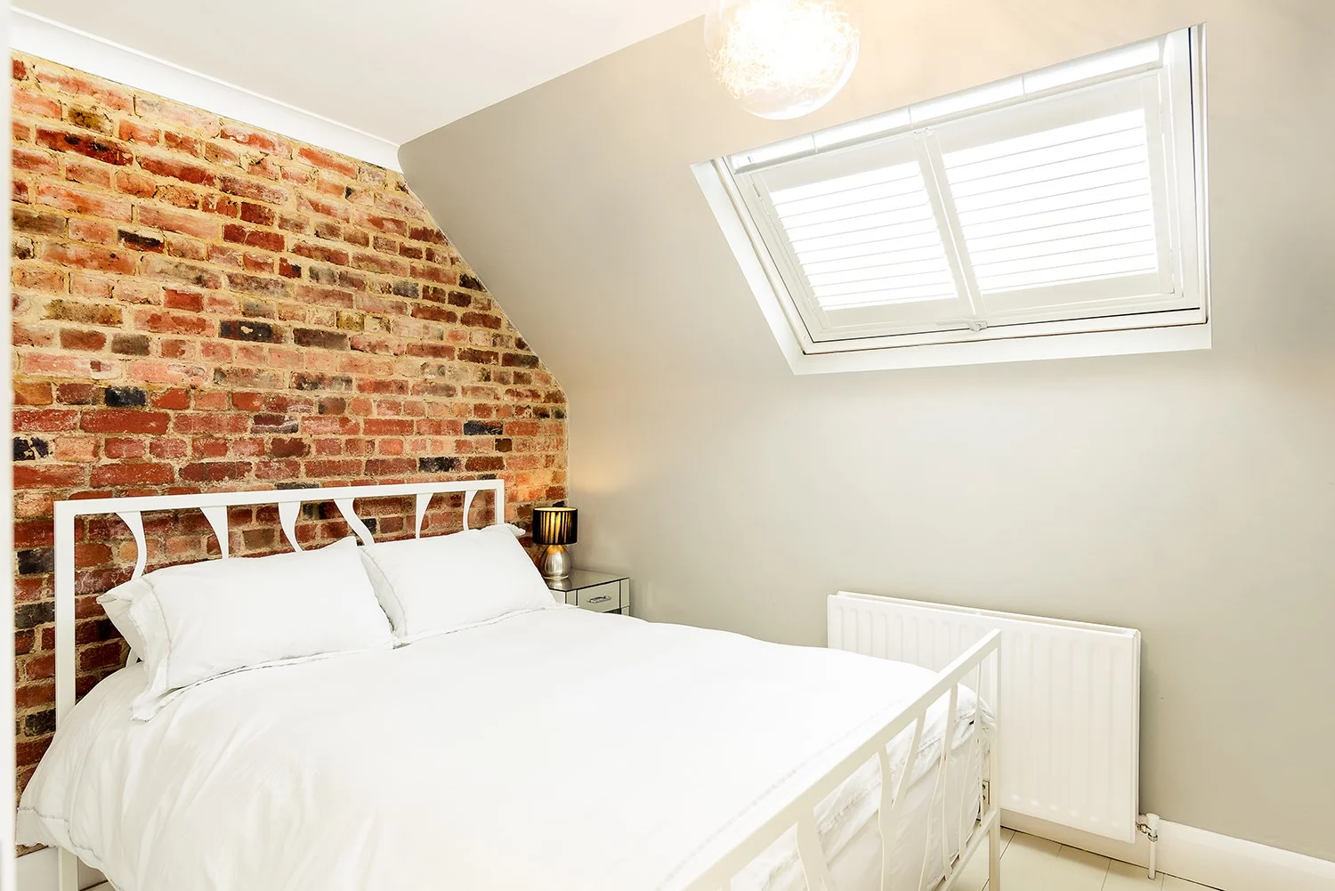 exposed brick wall in loft bedroom with skylight