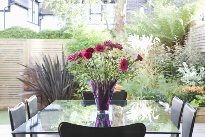 dining table with flowers and lush landscaping in garden beyond