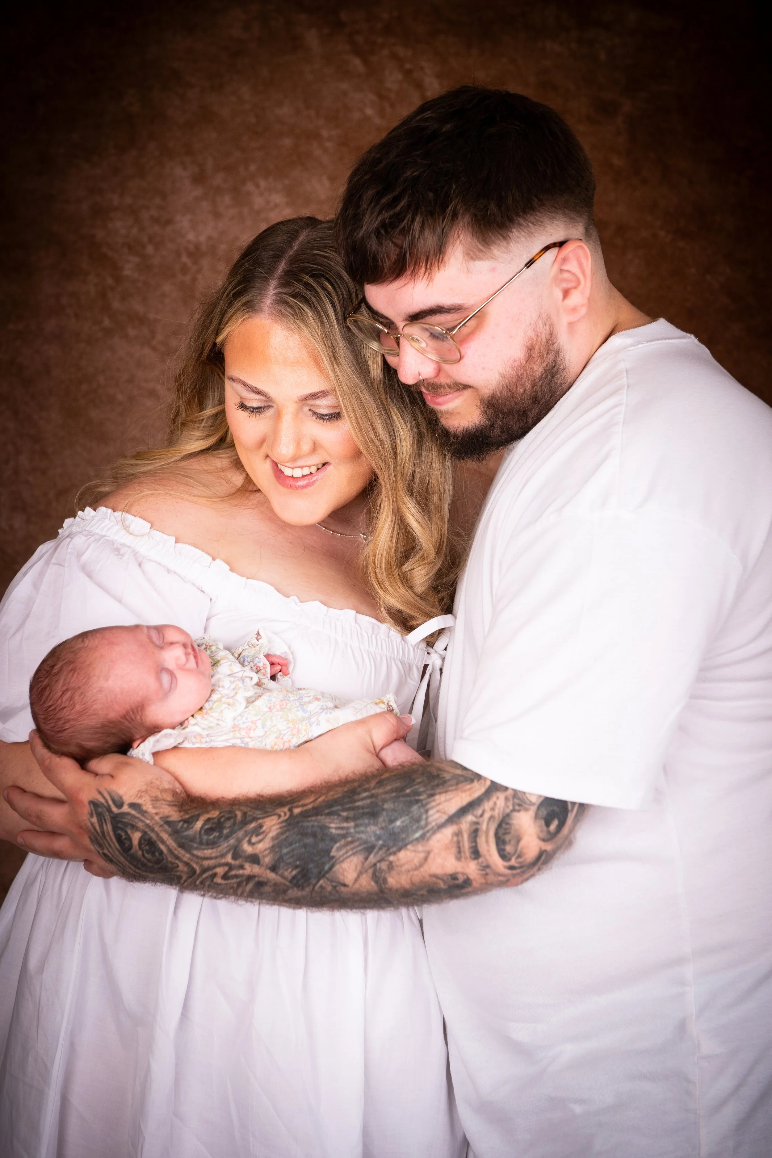 South Wales newborn photography studio session featuring parents standing and holding their new baby boy