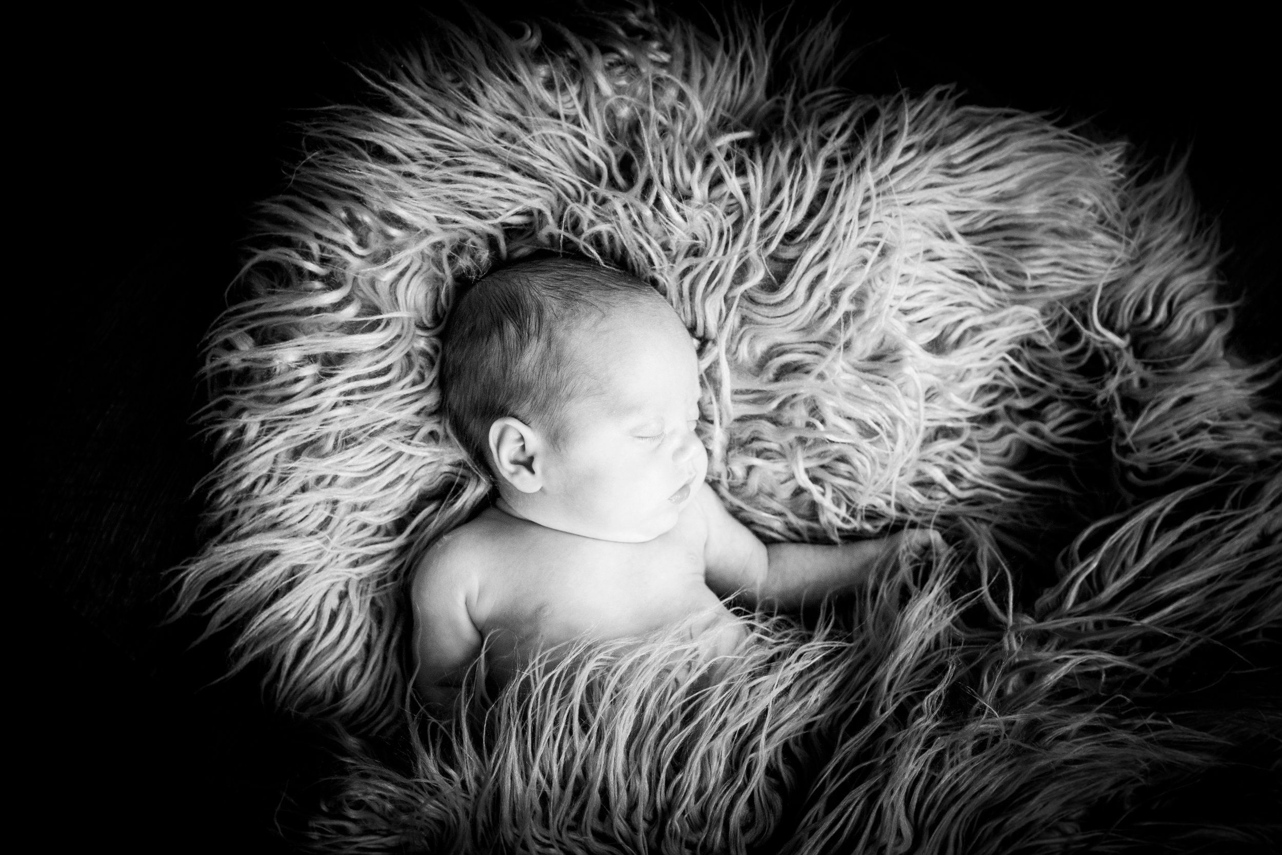 Sleeping newborn baby boy on a fluffy blanket captured by South Wales newborn photographer