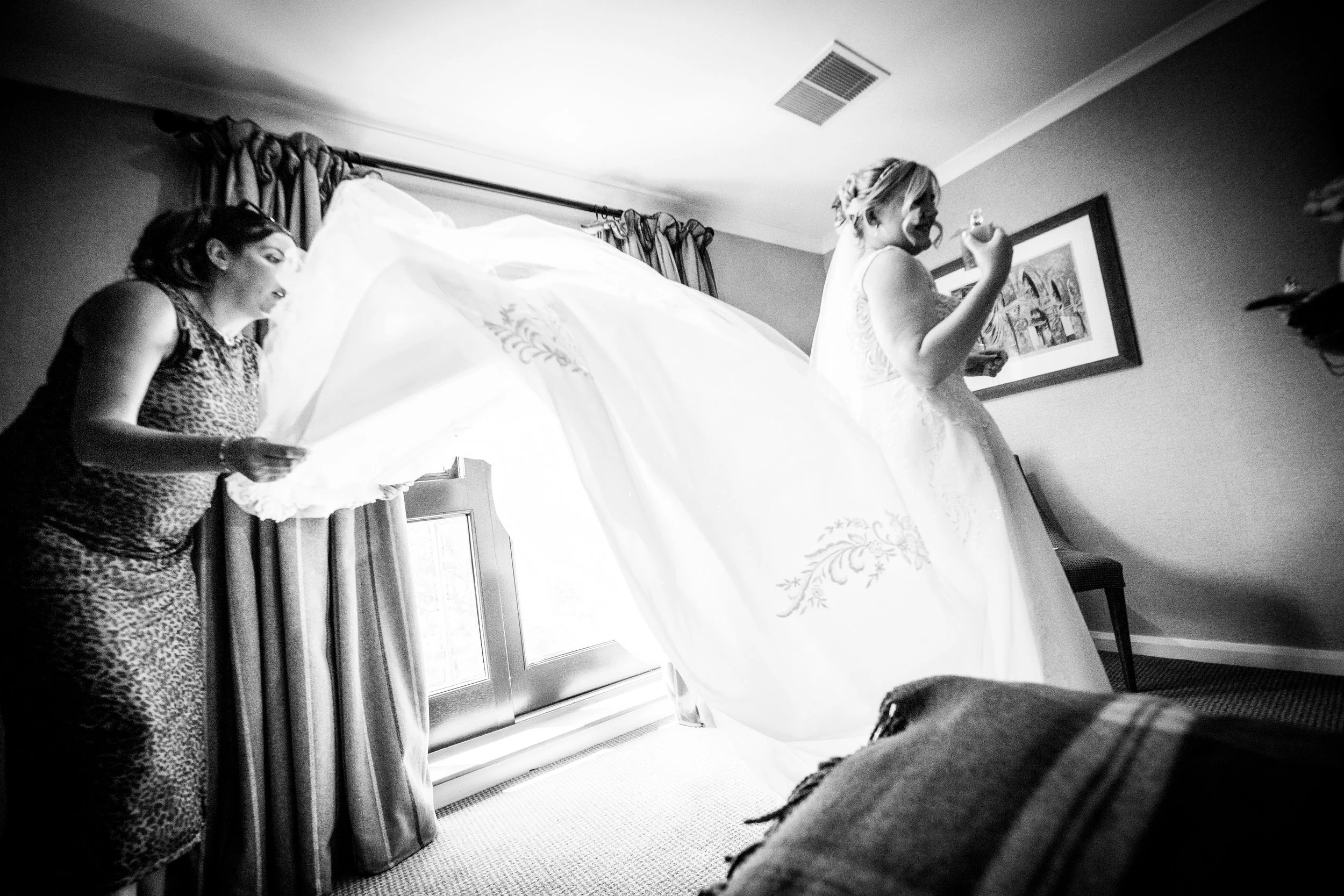 Black and white photograph of a bride having her long veil adjusted during morning prep at the Parkway Hotel Cwmbran