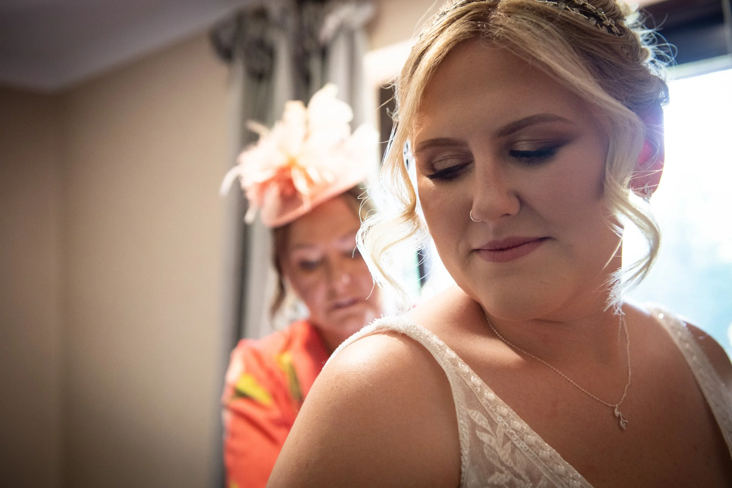 Close up portrait of a beautiful South Wales bride looking down while her wedding dress is fastened