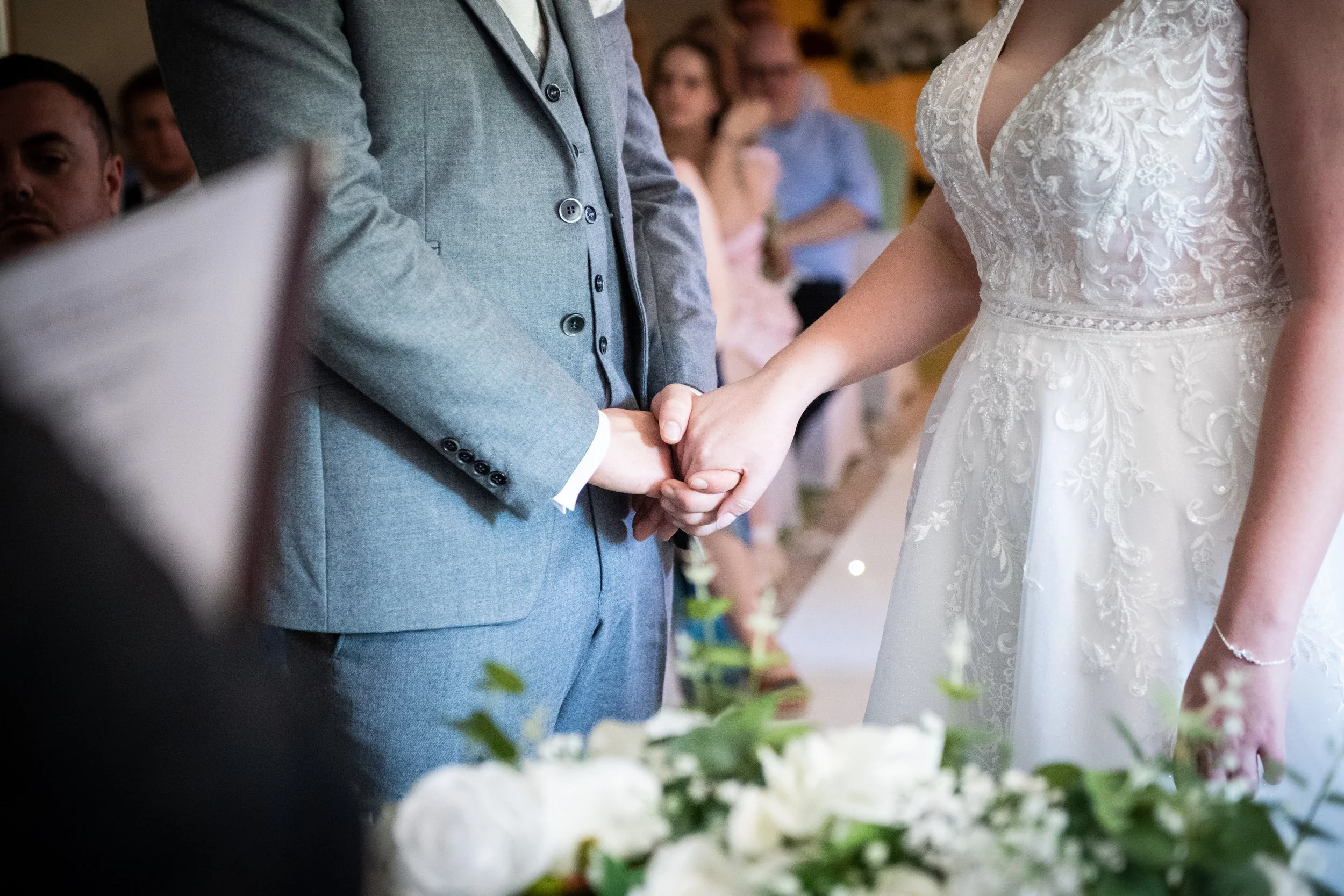 Close up detail of a bride and groom holding hands during their wedding ceremony at the Parkway Hotel in Cwmbran