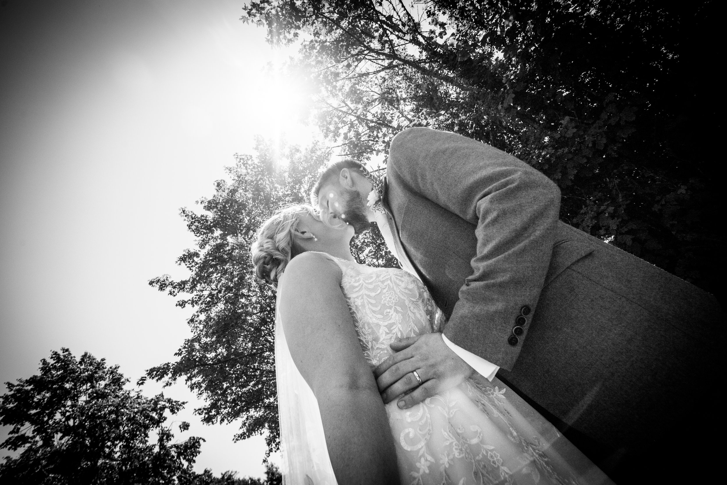 Romantic black and white portrait of a bride and groom about to kiss beneath the trees by local Pontypool wedding photographer