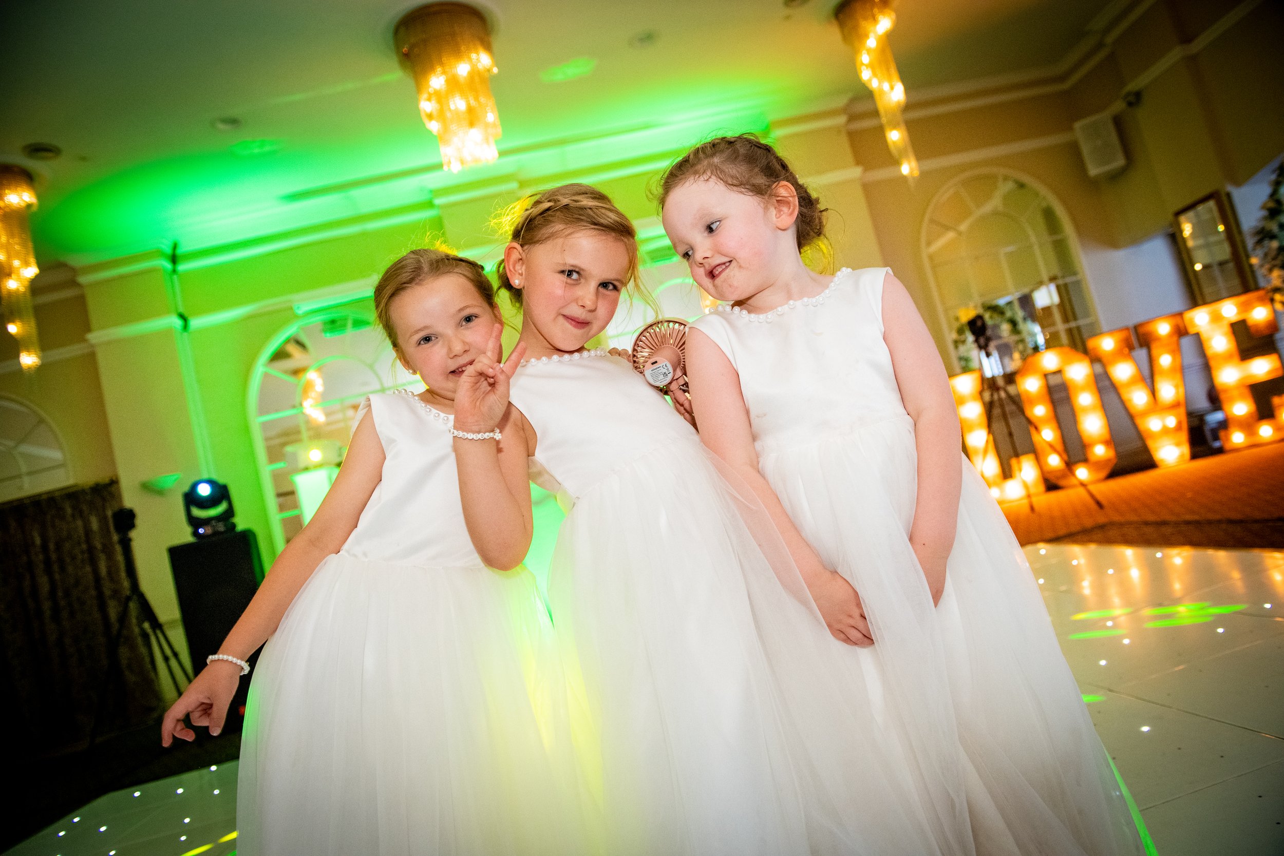 Three young flower girls having fun on the dancefloor in front of light-up LOVE letters at a Parkway Hotel wedding reception