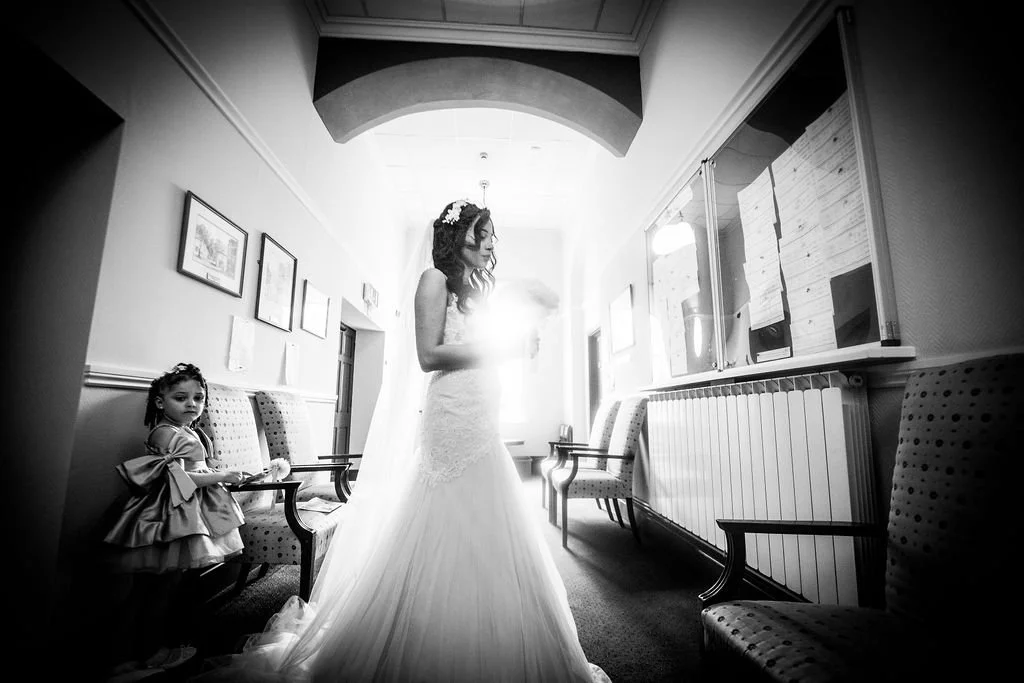 Black and white photo of a bride and flower girl waiting in the hallway at Pontypool Registry Office
