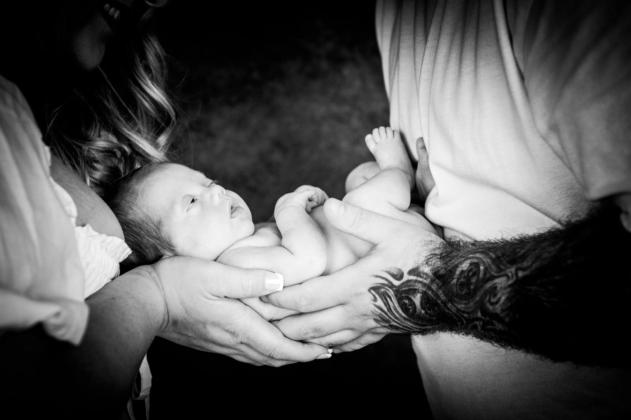 A detailed black and white close-up photograph of parents' hands gently holding their newborn baby during a studio photoshoot with Emotion Picture Photography in Pontypool, South Wales.these were all taken in belle vu