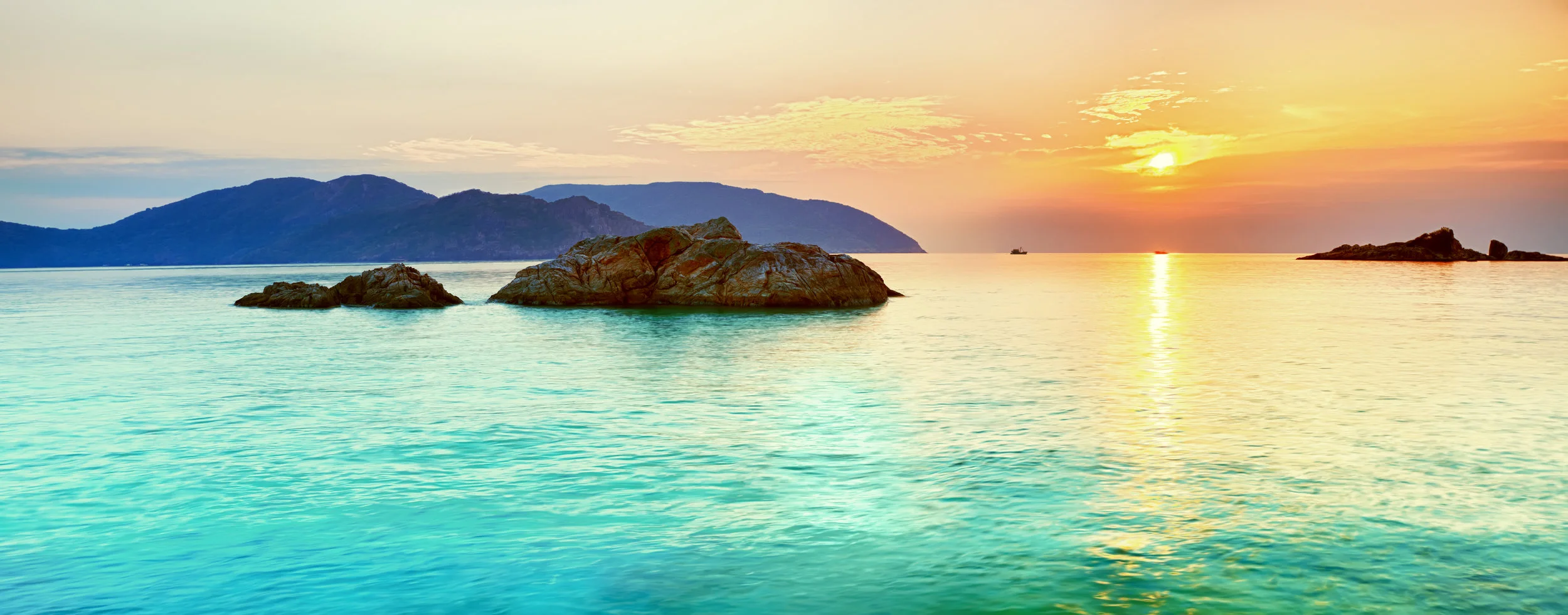 turquoise ocean sunset and mountains.jpg