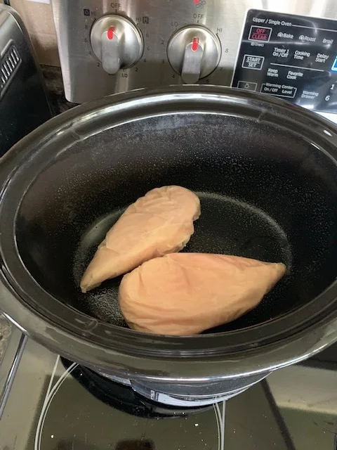 Place chicken (frozen or thawed, doesn’t matter) in a crock pot. Season how you’d like, and cook on high for 3-4 hours.