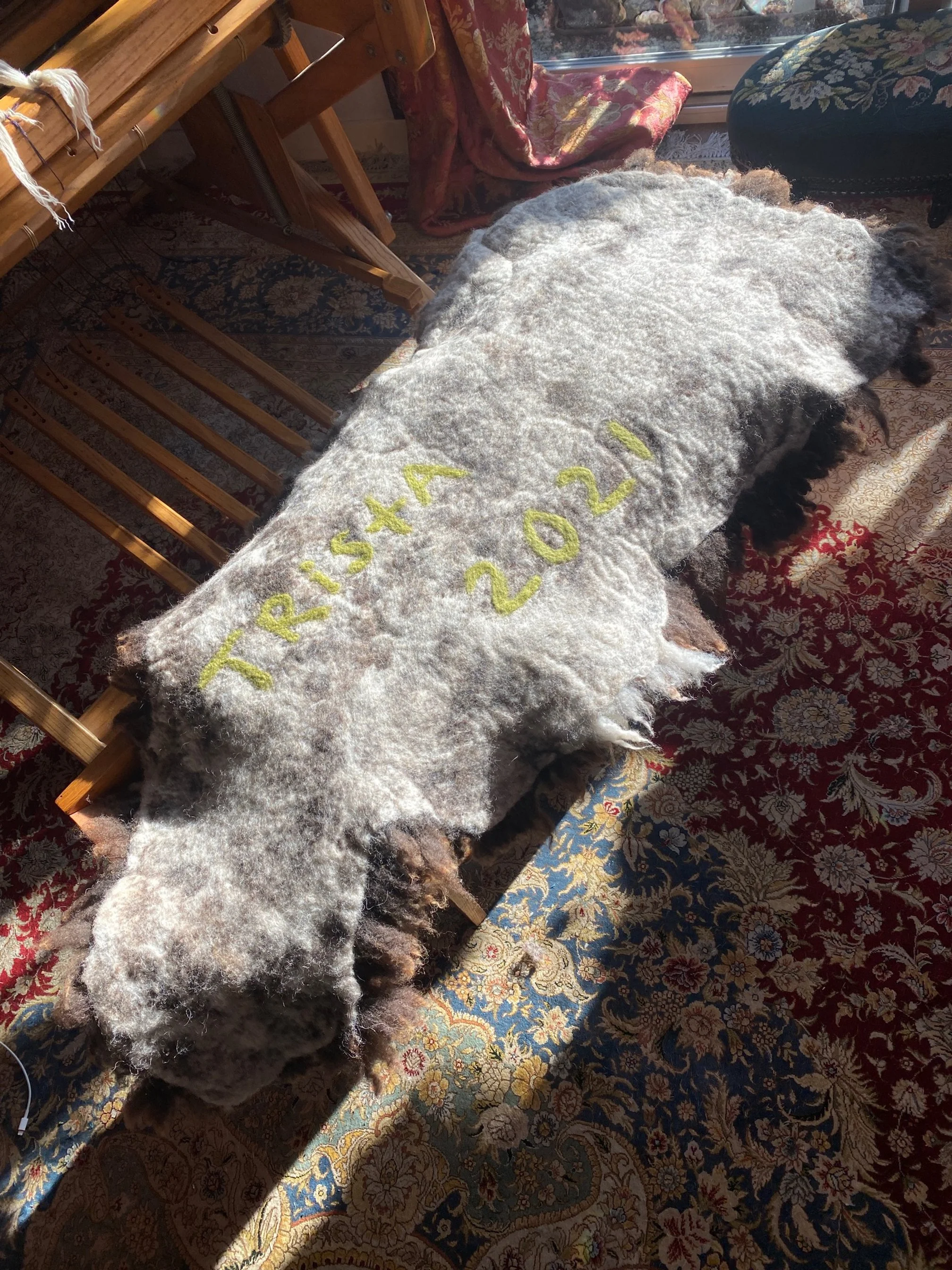 Backside of woolly bench pad with the sheep name needle-felted on the surface.
