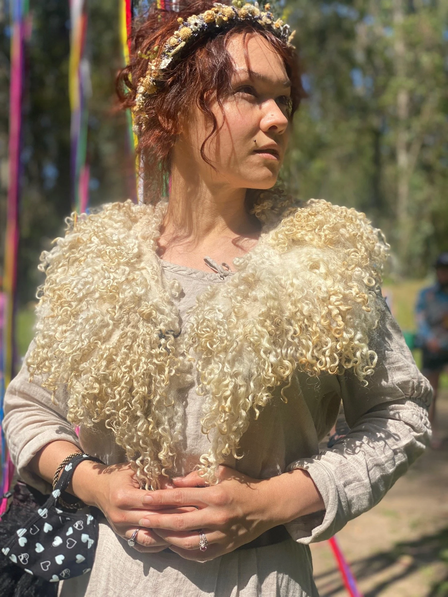 Woman wearing sheepskin collar with curly wool locks dangling.