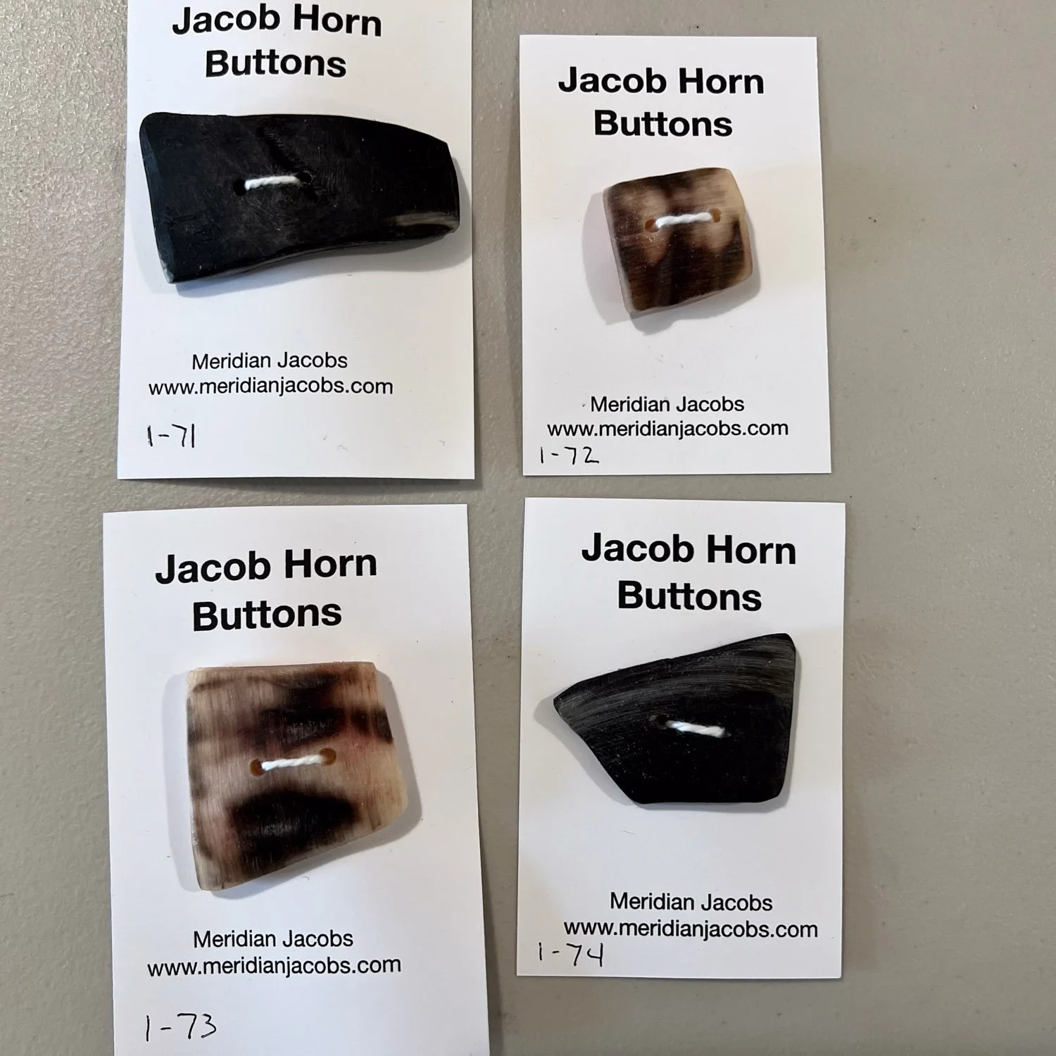 Four Jacob horn buttons on individual cards.
