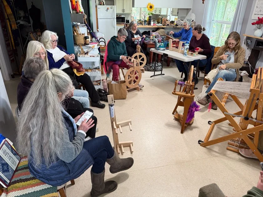 Group of women working on crafts--spinning, weaving, knitting.