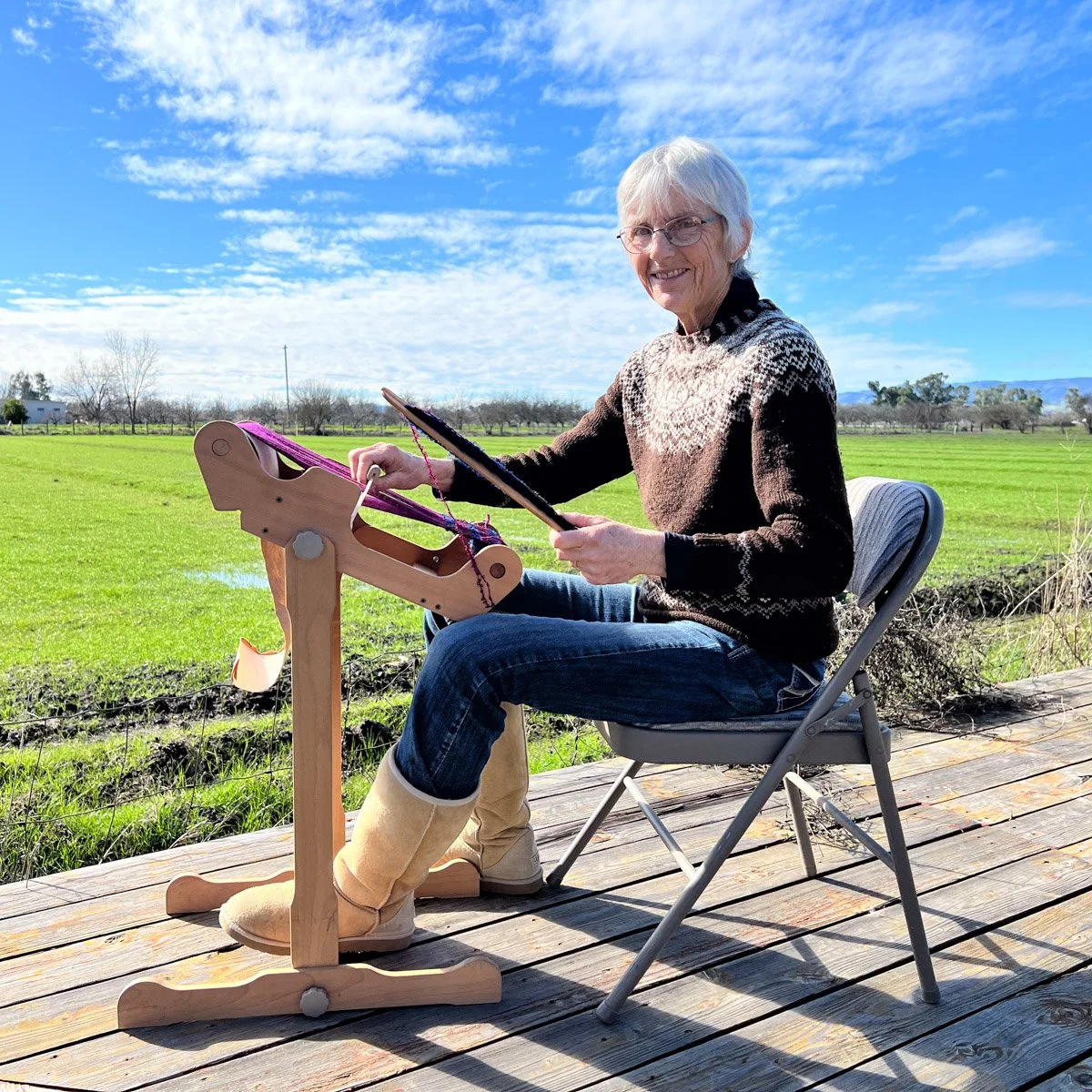 Robin working on a rigid heddle loom outside.