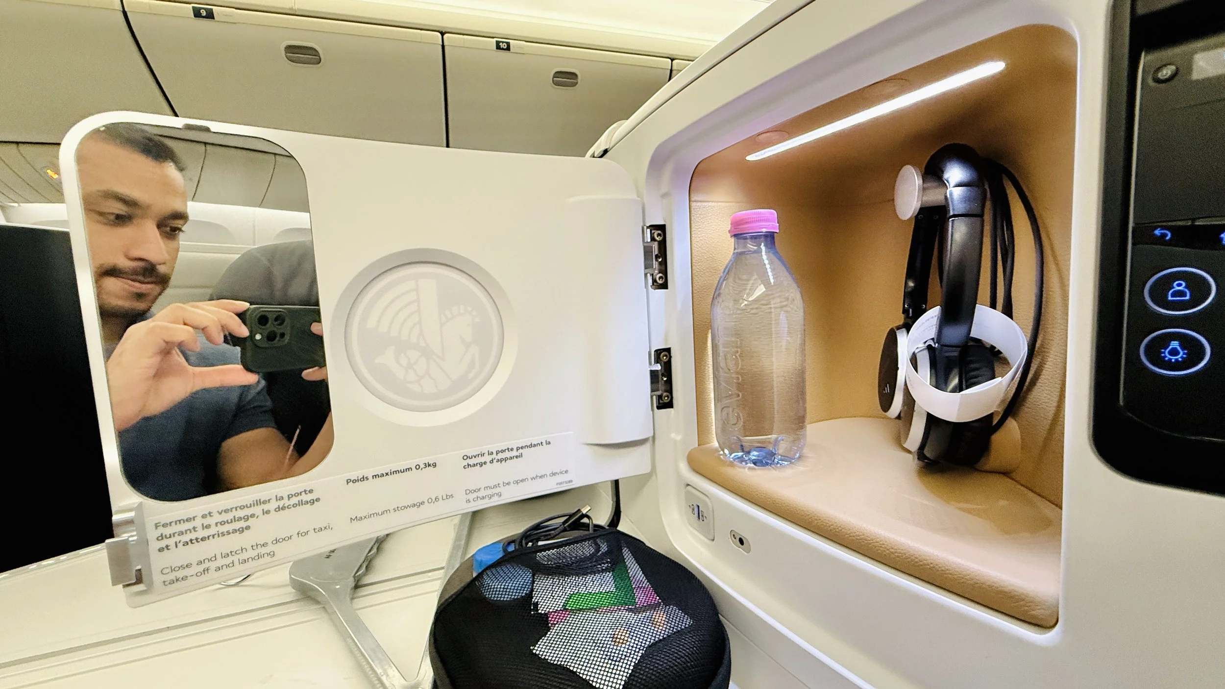 The side compartment hides a mirror, a bottle of Evian water and noise cancelling headphones