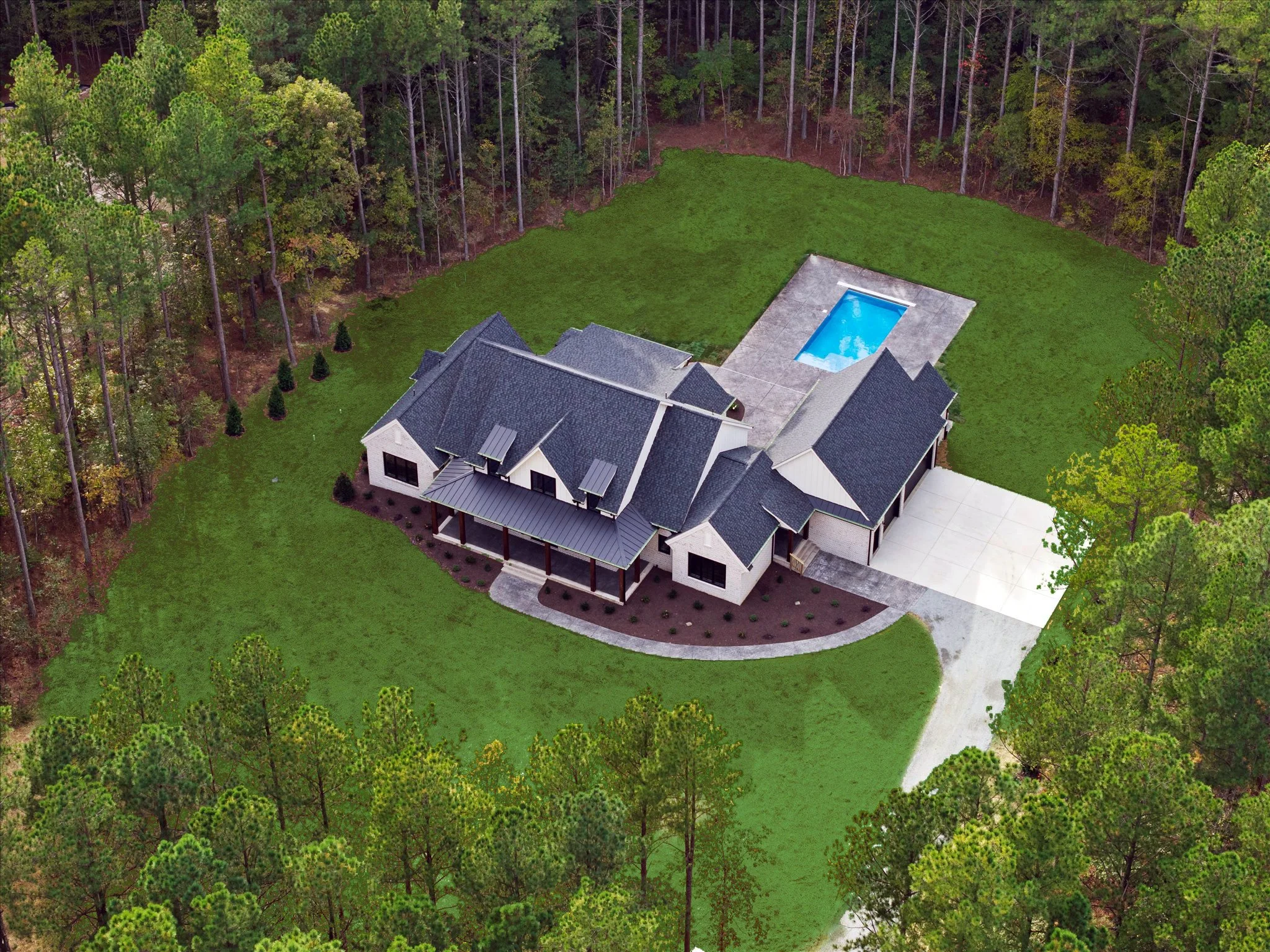 Aerial view of a modern house with a backyard and swimming pool surrounded by trees.
