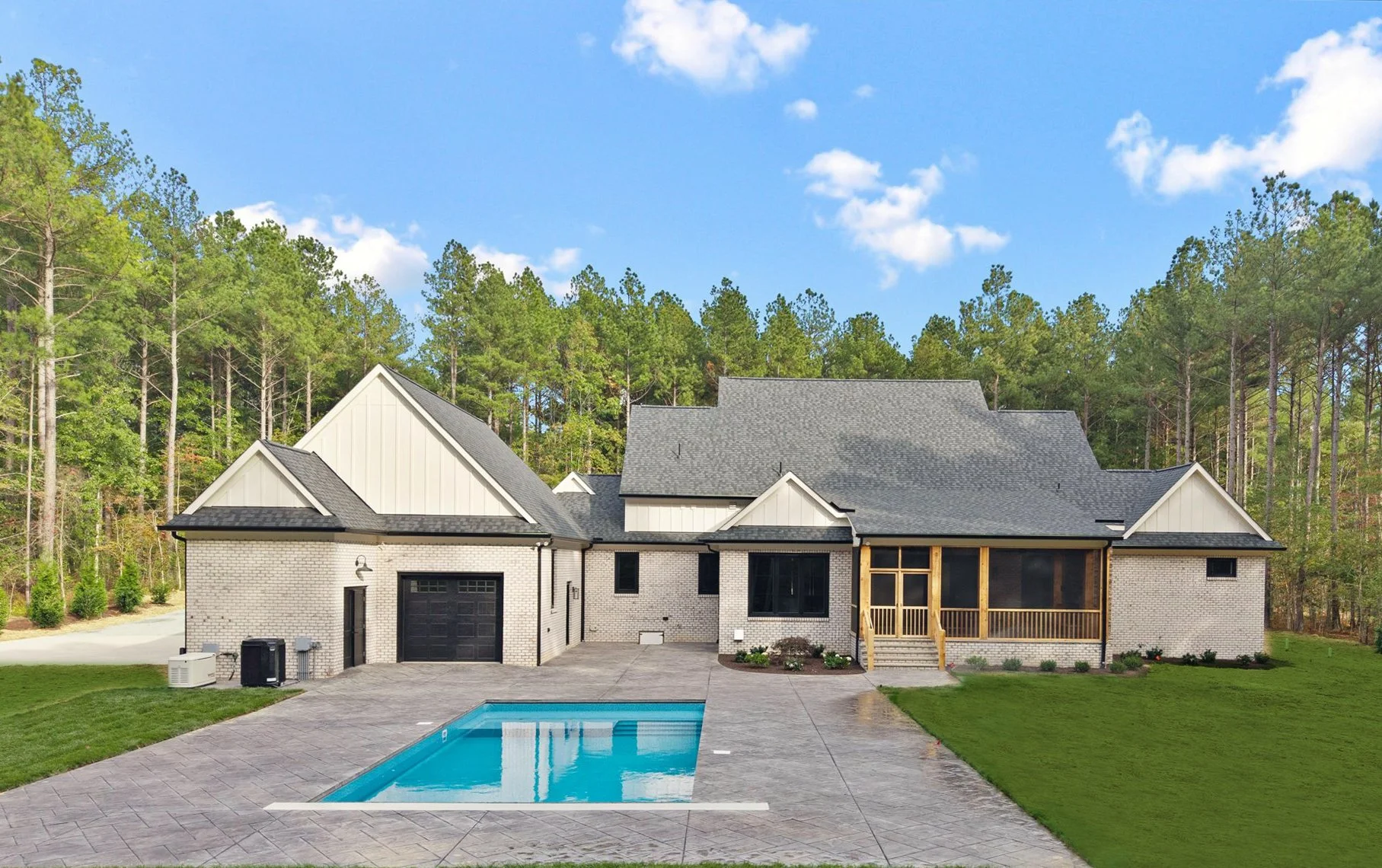 Modern house with brick exterior, screened porch, and swimming pool in backyard, surrounded by trees.
