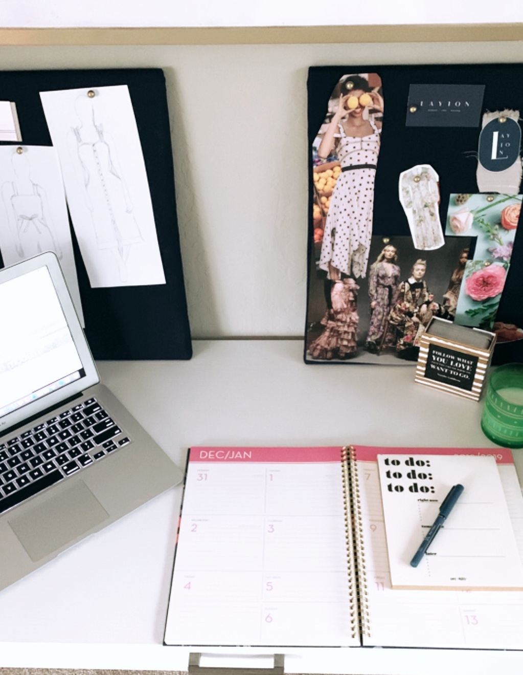 A photo of a work desk including a planner, calendar and laptop.