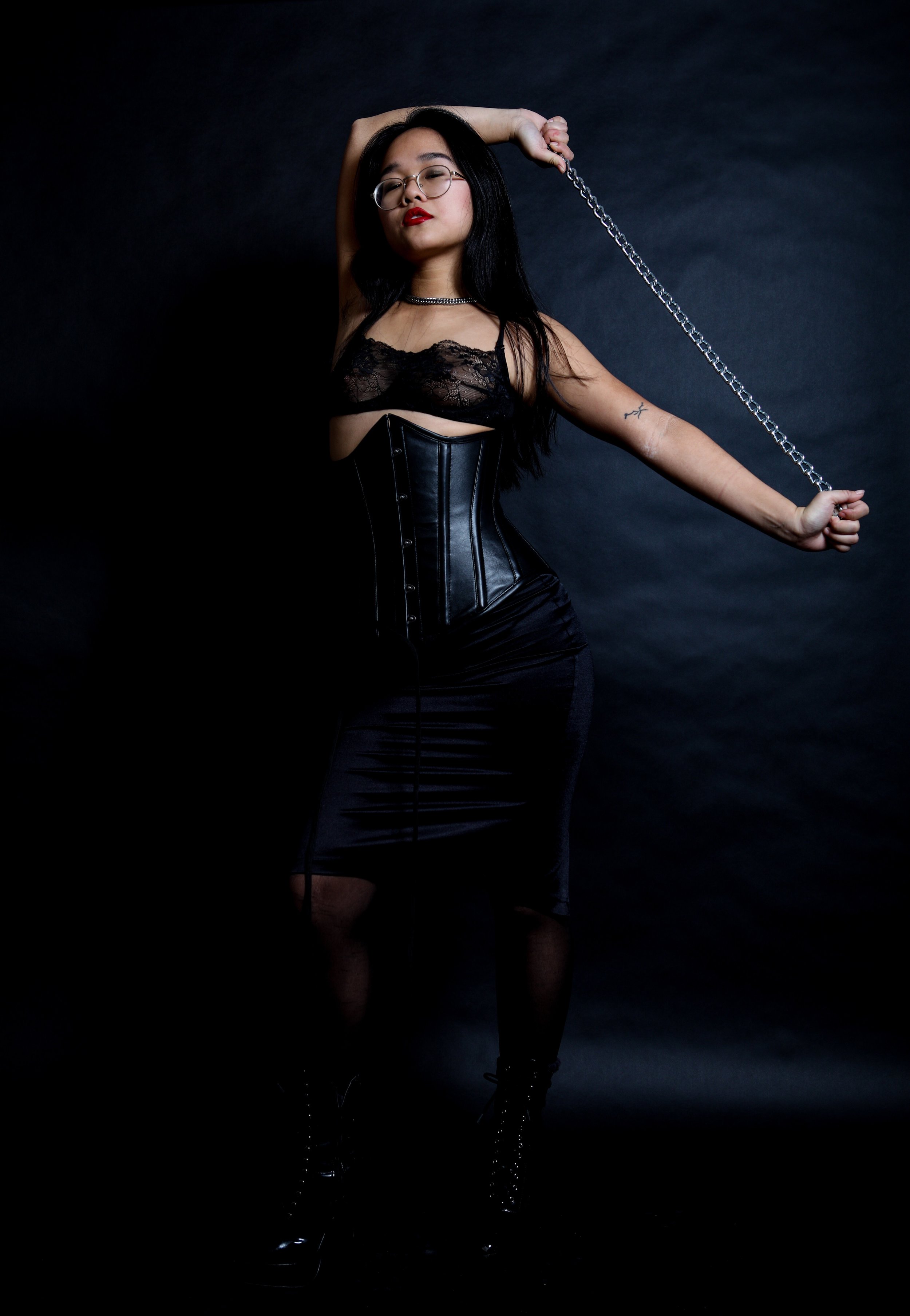 Chinese Dominatrix Empress Wu In an all black outfit: lingerie, leather corset, nylons, and vinyl boots, New York Prodomme is ready to take all of your fetishes