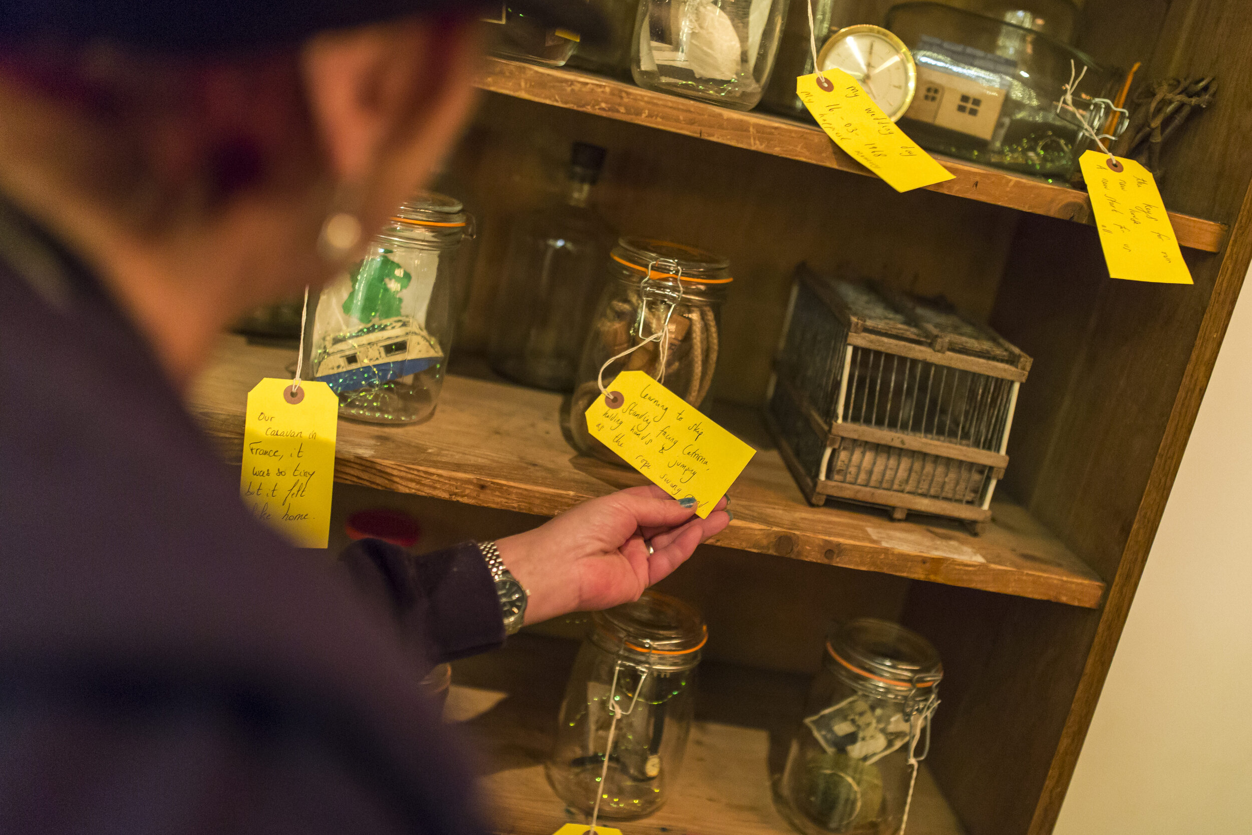  A man reads a yellow tag attached to a mason jar. 