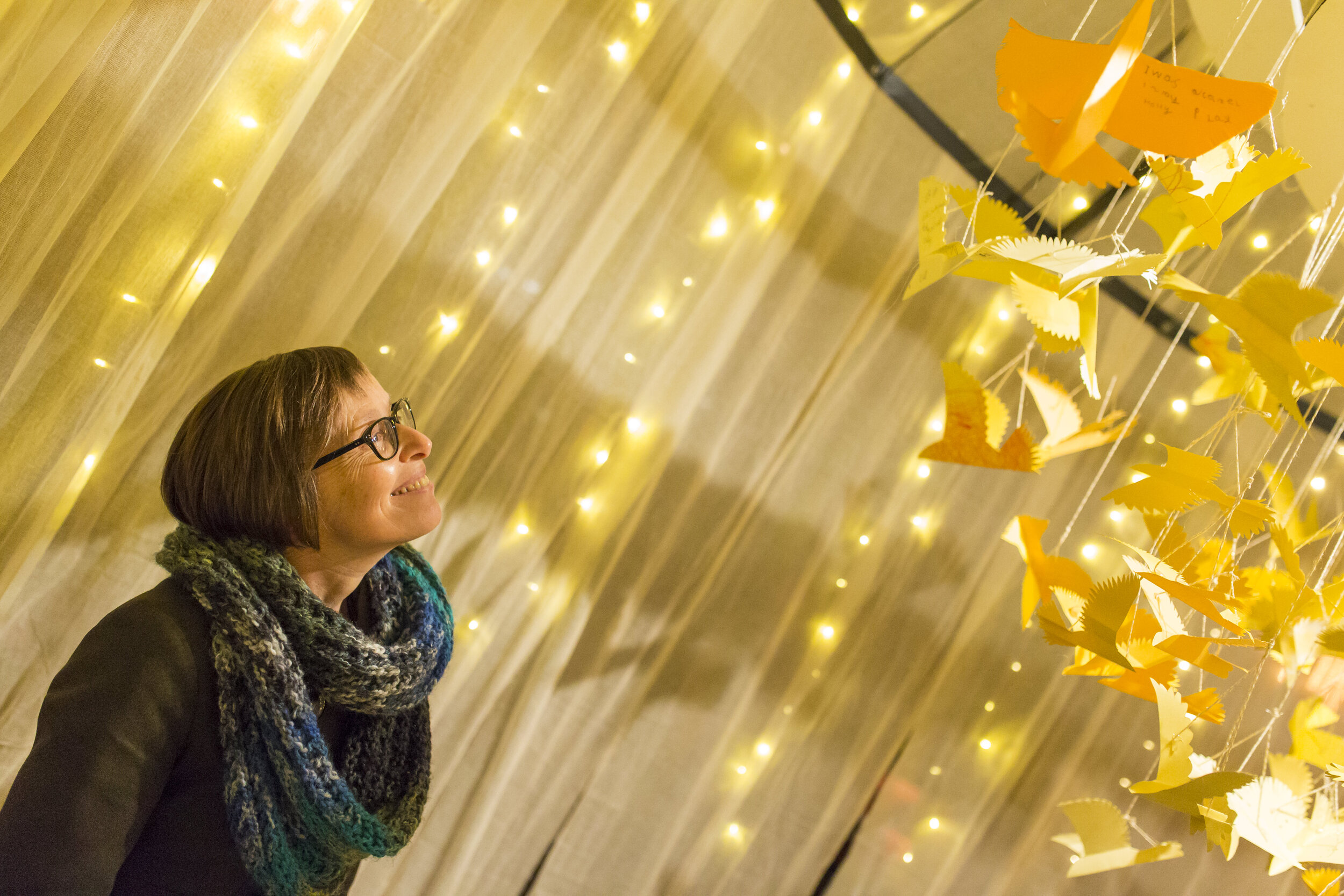  A woman looks up towards the origami birds. 