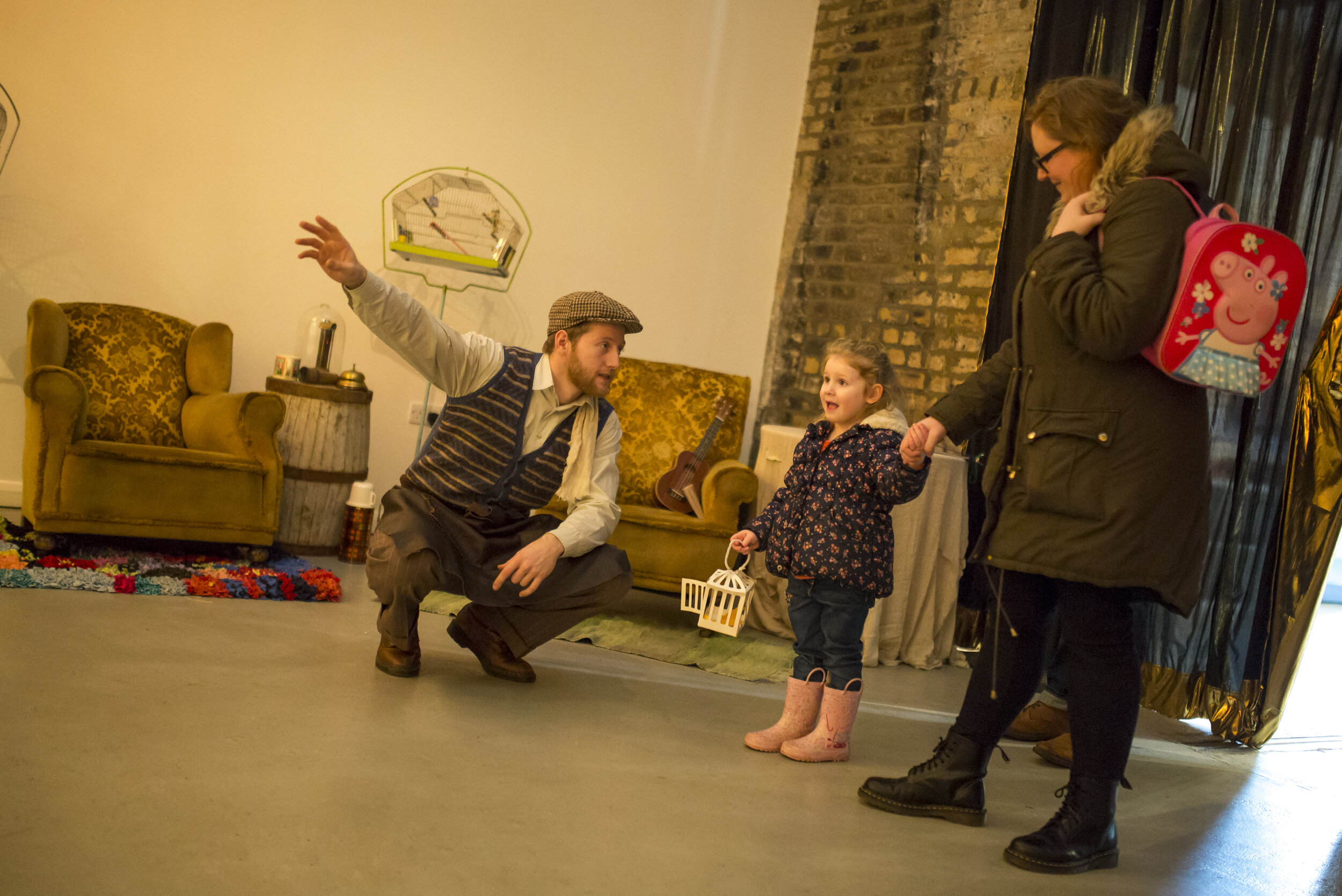  A man wearing a flat-cap explains to a child holding her mothers hand. 