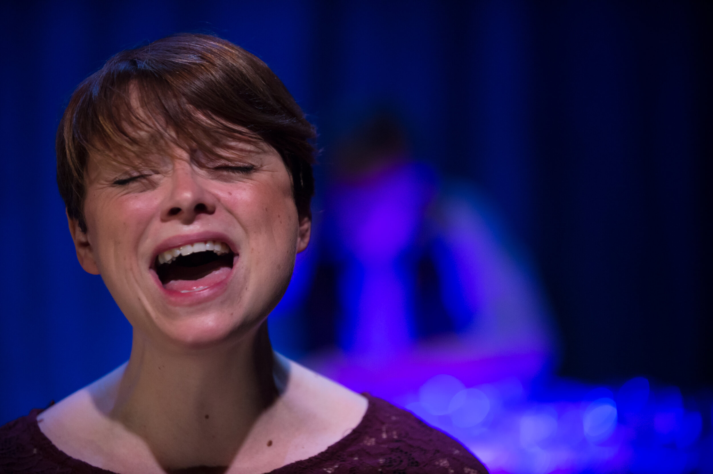  A woman singing with an expressive facial expression. 