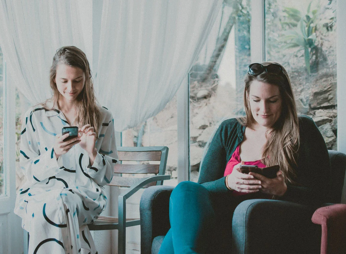 two seated women looking phones.jpg